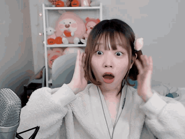 a girl with a surprised look on her face is sitting in front of a microphone