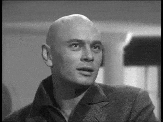 a man with a bald head is looking at the camera in a black and white photo