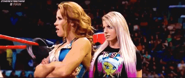 two female wrestlers are standing next to each other in a ring .