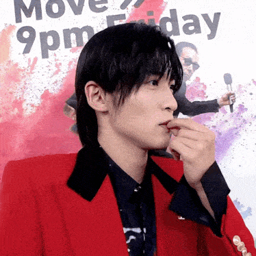 a man in a red jacket is holding a microphone in front of a sign that says 9pm friday