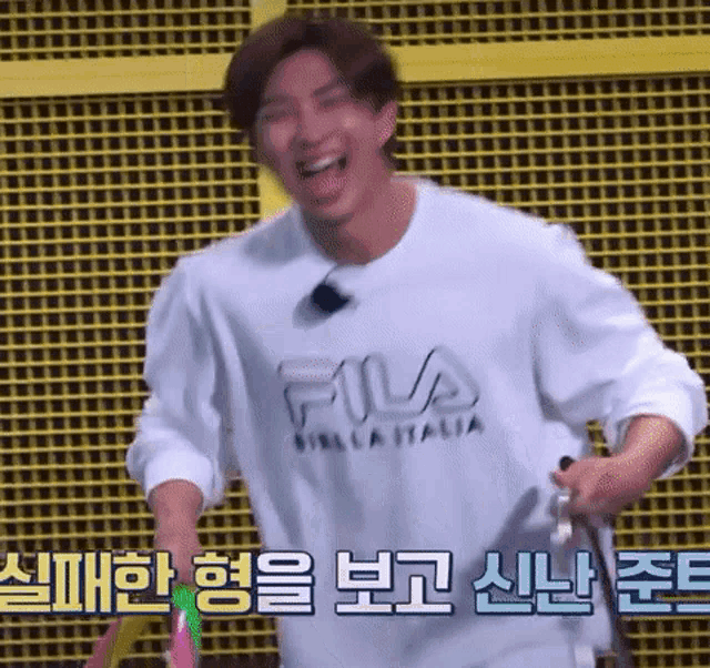 a man wearing a fila shirt is holding a tennis racket
