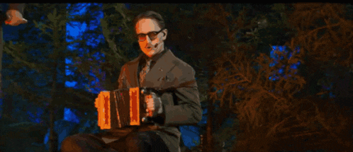 a man in a suit and tie is holding an accordion and singing