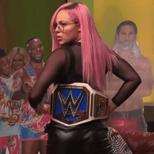 a woman with pink hair is wearing a wrestling belt with the letter w on it