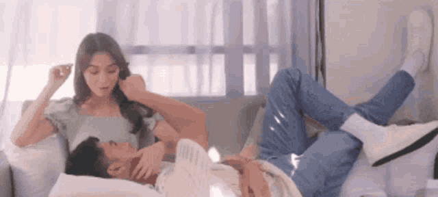 a man and a woman are laying on a couch with their legs up .