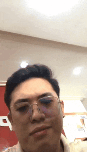 a man wearing glasses and a white shirt making a funny face