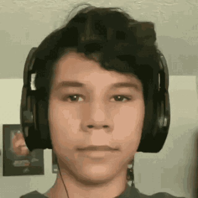 a young man wearing headphones is looking at the camera in a living room .