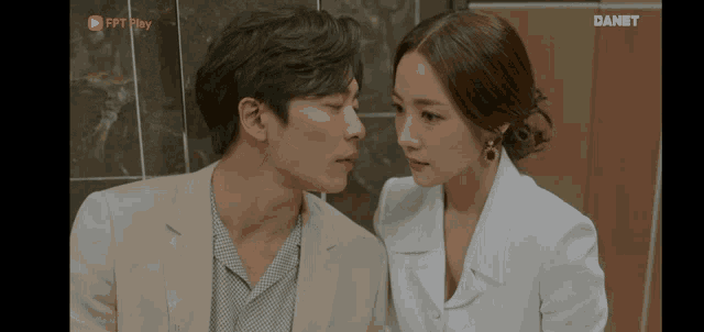 a man and a woman are looking at each other with a danet logo in the corner