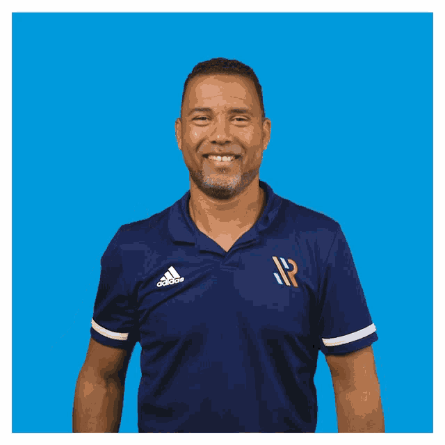 a man in a blue adidas shirt gives a thumbs up