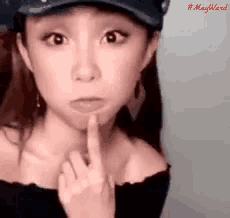 a woman wearing a hat is making a silly face with her finger on her lips