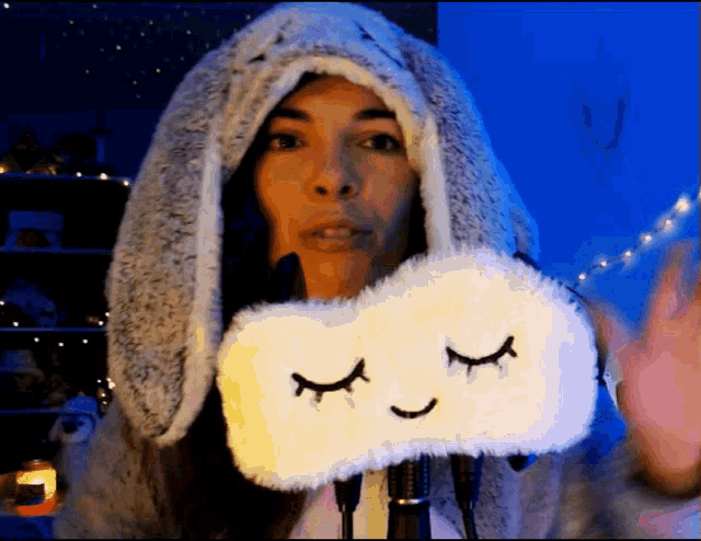 a woman wearing a bunny hat holds a sleep mask