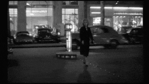a black and white photo of a woman walking on a street