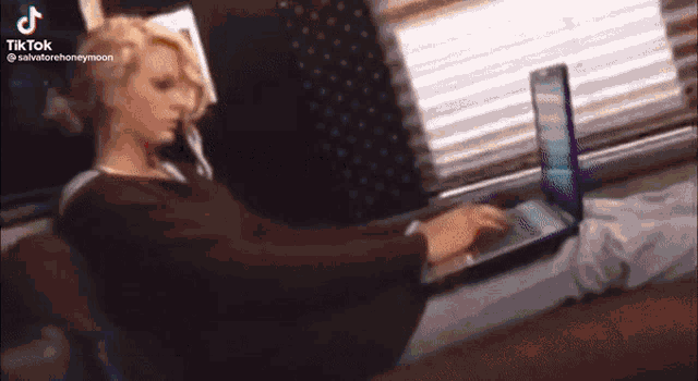 a woman is sitting on a couch typing on a laptop computer .
