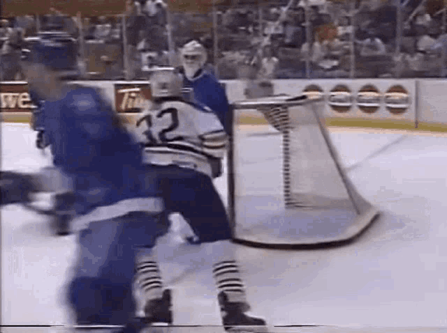 two hockey players are playing a game on the ice and one of them has the number 32 on his jersey .
