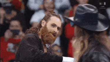 a man with a beard is standing next to a woman wearing a hat .