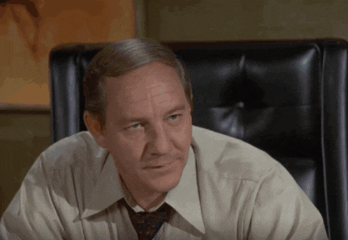 a man wearing a white shirt and tie is sitting in a chair