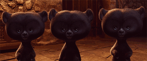 three black teddy bears are standing next to each other in a dark room