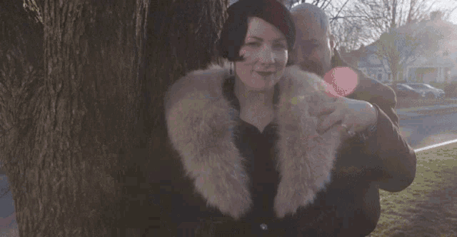 a woman wearing a fur coat stands next to a man