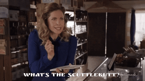 a woman in a blue shirt is holding a piece of paper and says what 's the scuttlebutt hallmark