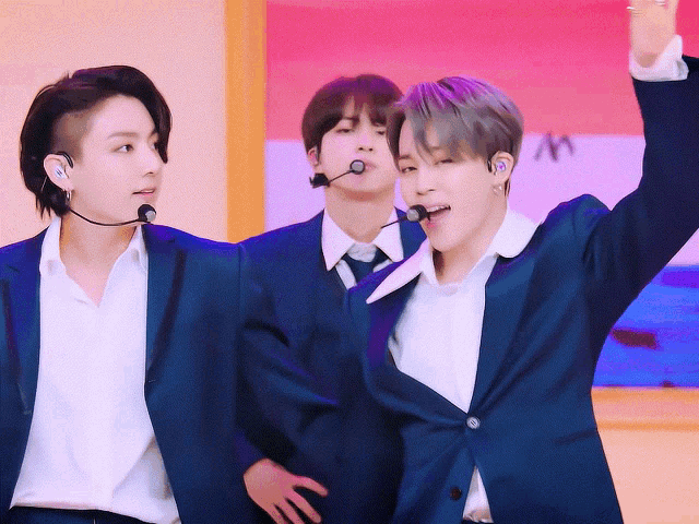 three men wearing suits and ties are standing next to each other with their hands in the air