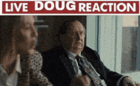 a man in a suit and tie is sitting next to a woman in front of a live doug reaction sign