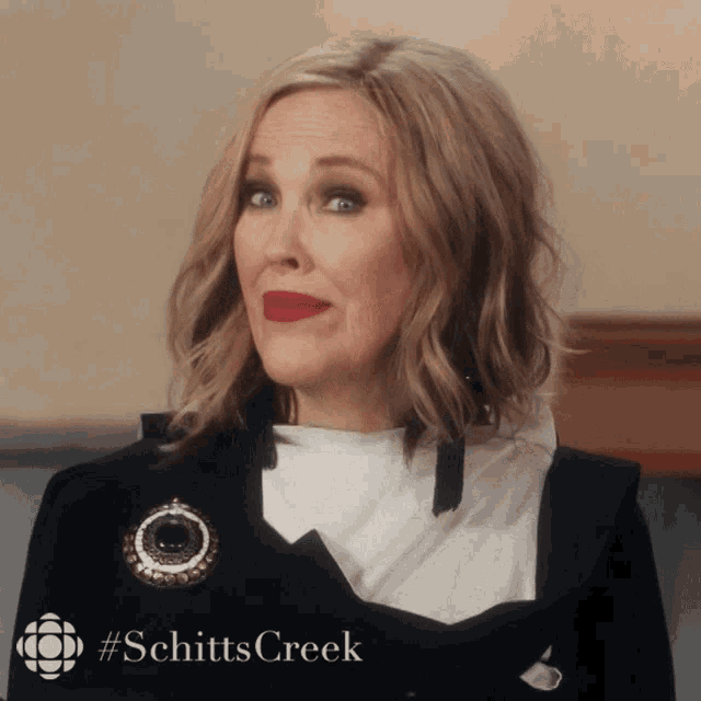 a woman with red lipstick and a #schittscreek logo