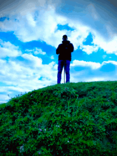 a person standing on top of a hill with a blue sky behind them