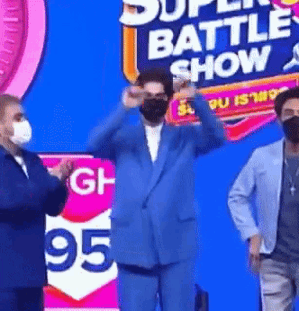 a man in a blue suit is standing in front of a super battle show sign