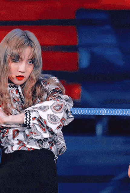 a woman wearing a paisley shirt and black skirt is dancing on a stage