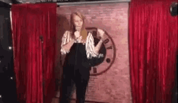 a woman is standing in front of a microphone in front of a red curtain .