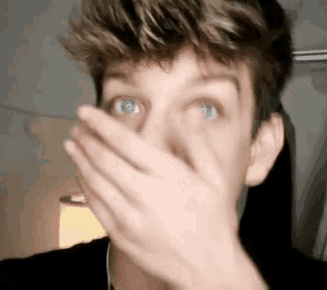 a close up of a person covering their face with their hands .