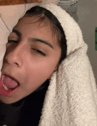 a woman with a towel on her head is sticking out her tongue