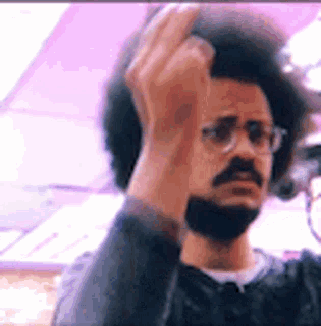 a man with a beard and afro is giving the middle finger .
