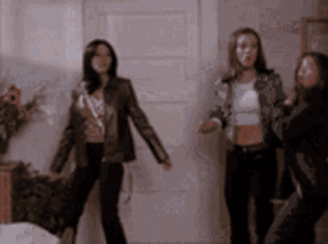 three women are dancing in a room in front of a white door