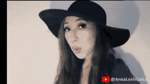 a woman wearing a black hat with a youtube play button in the background