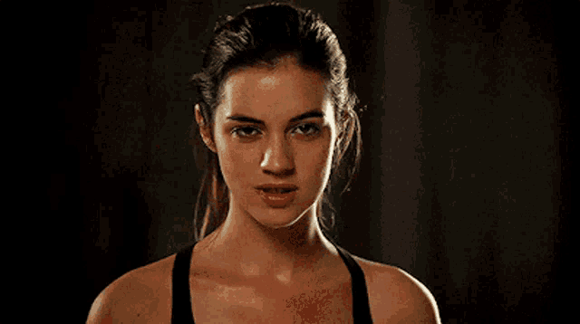 a woman in a black tank top is smiling and making a face