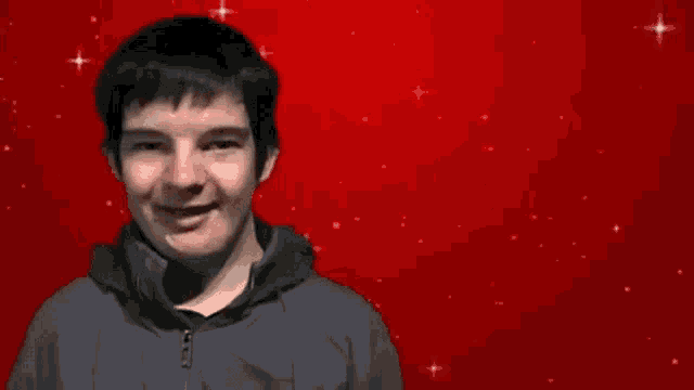 a young man is smiling in front of a red background with the words it 's christmas