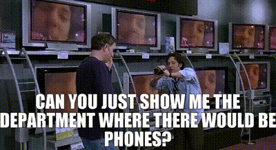 a man is standing in front of a row of televisions with the caption can you just show me