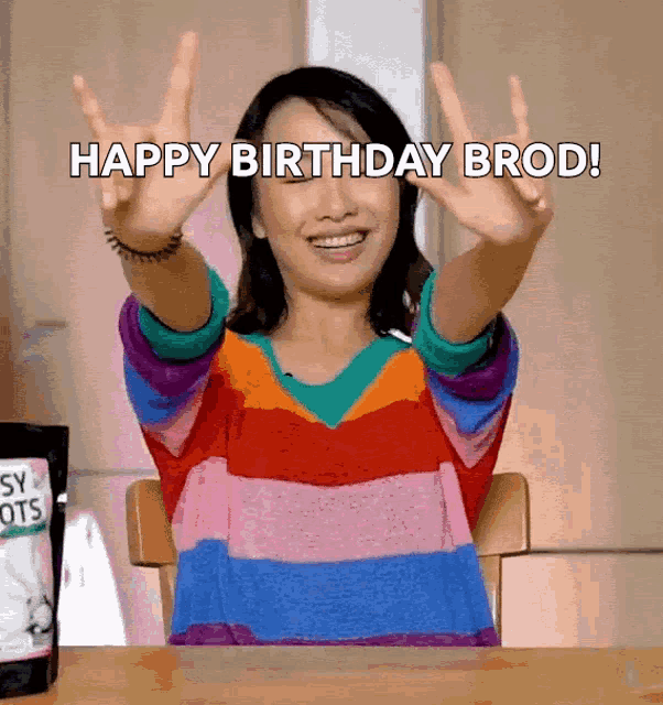 a woman in a rainbow striped shirt is saying happy birthday bro