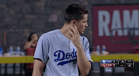 a man in a dodgers jersey is standing in front of a ram sign