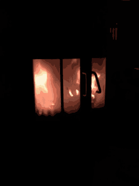 a fire is burning in a dark room with a door that is open