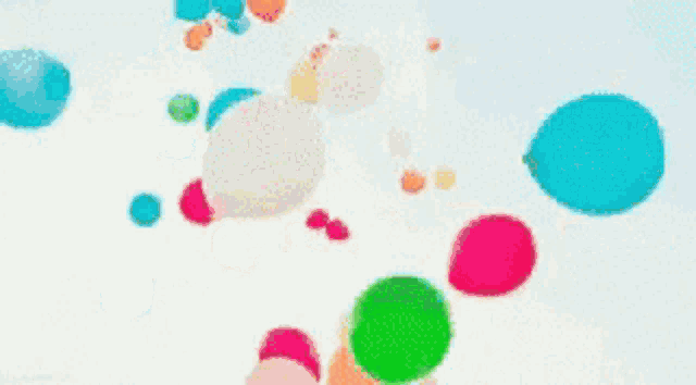 a bunch of colorful balloons are flying in the air on a white background .