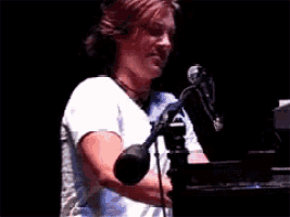 a woman in a white shirt is singing into a microphone on a stage