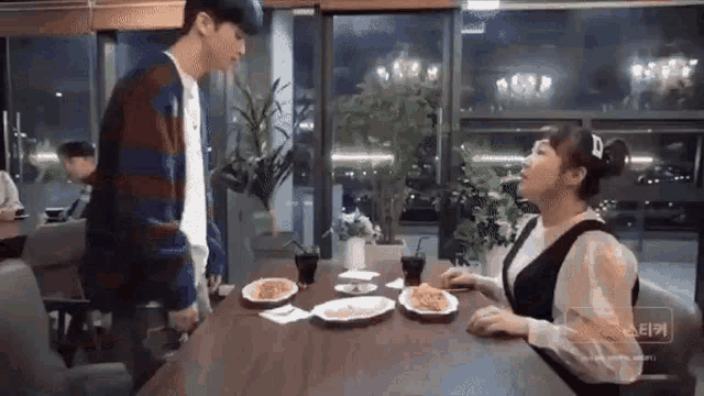 a man and a woman are sitting at a table in a restaurant with plates of food .