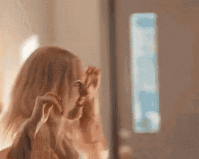 a woman is looking at herself in a mirror while applying makeup .