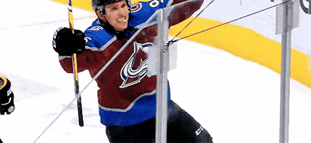 a hockey player in a colorado avalanche jersey is holding a stick