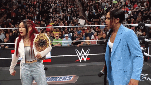 two women are in a wrestling ring with a sign that says snickers