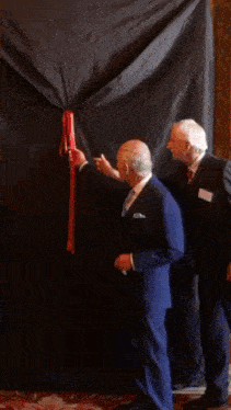 a picture of a man in a suit behind a black curtain