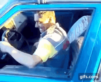 a man is driving a blue car with a gifs.com logo on the bottom right