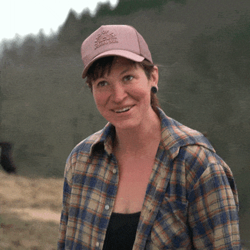 a woman wearing a plaid shirt and a hat that says rising sun