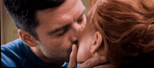 a man and a woman are kissing each other in a room .